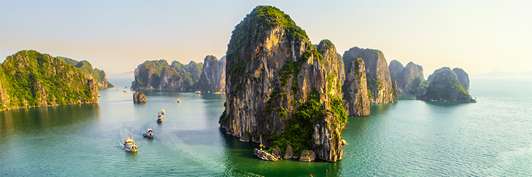 Boats driving around a rock island. 