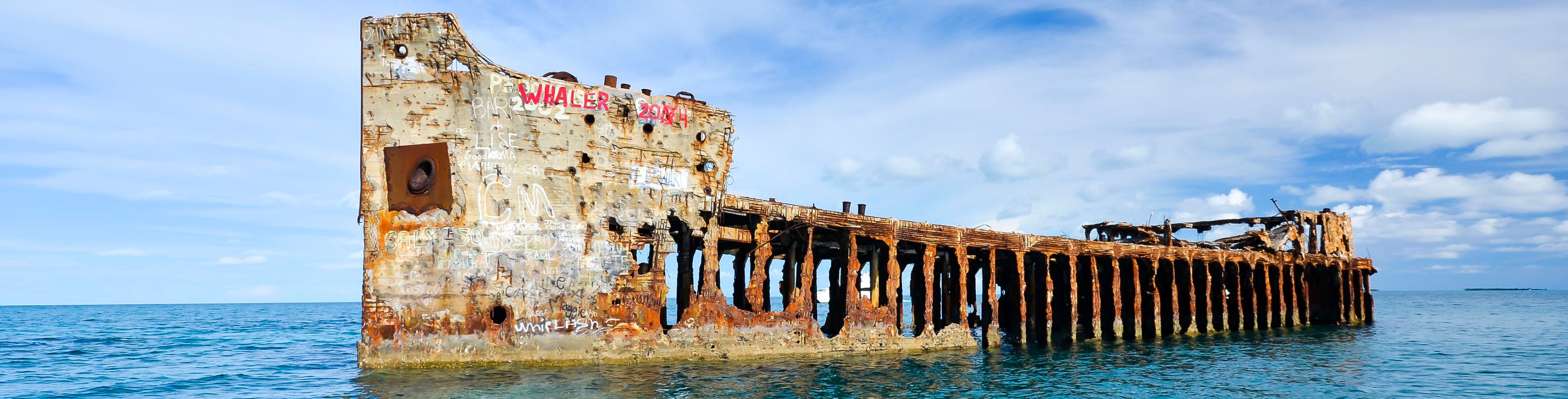 Ruins of a ship sitting on top of the ocean water. 