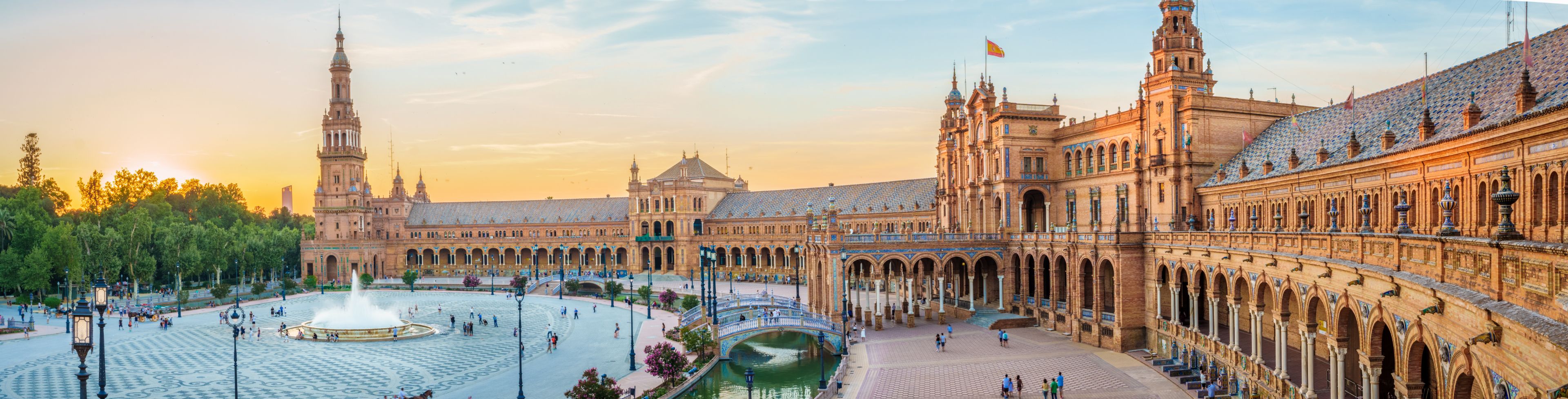 Large building structure with people milling about in front of the building. 