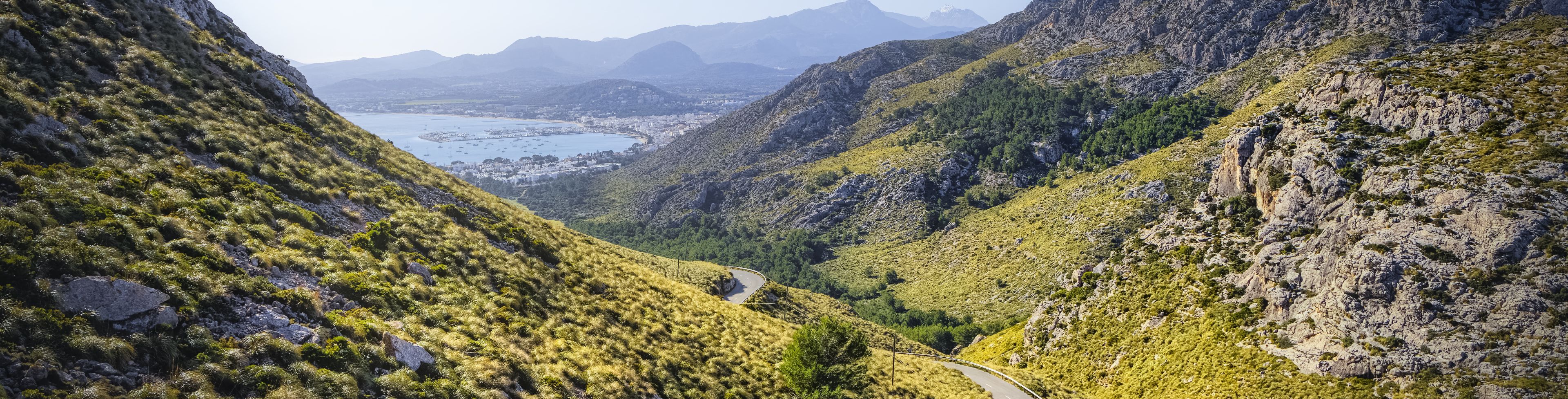 Road weaving in a small valley between two larger hills. 
