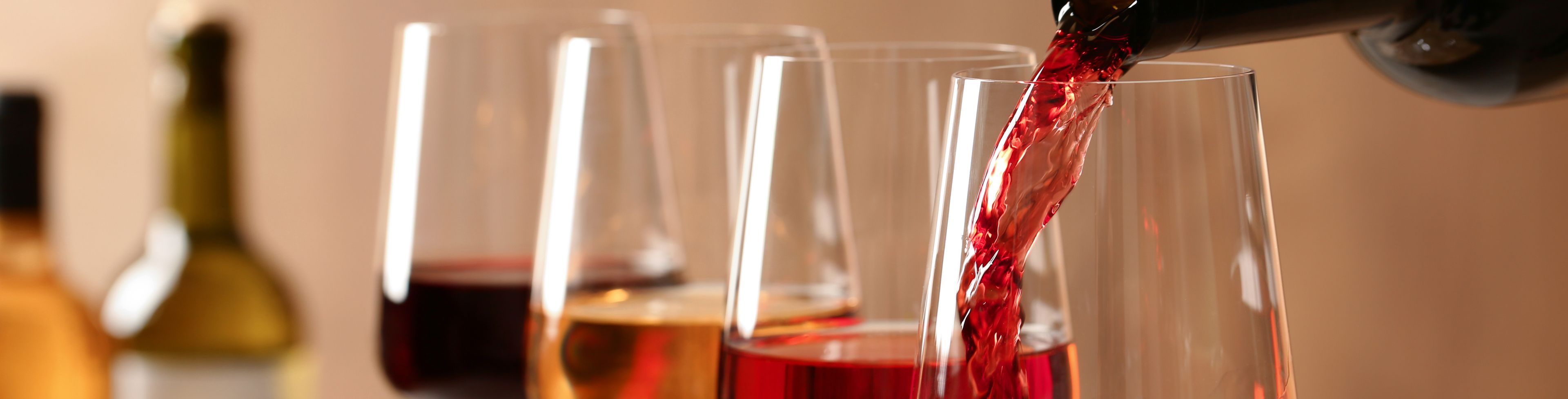 Four wine glasses, one being filled by a bottle of wine. 