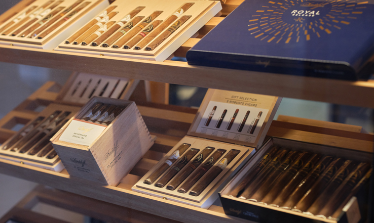 Many different cigars sitting in a variety of cases on display.