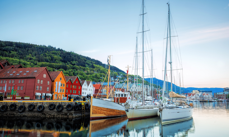 Sail boats docked at a dock lining buildings facing the ater