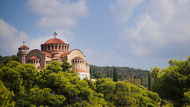 An old building on a hillside filled with trees. 