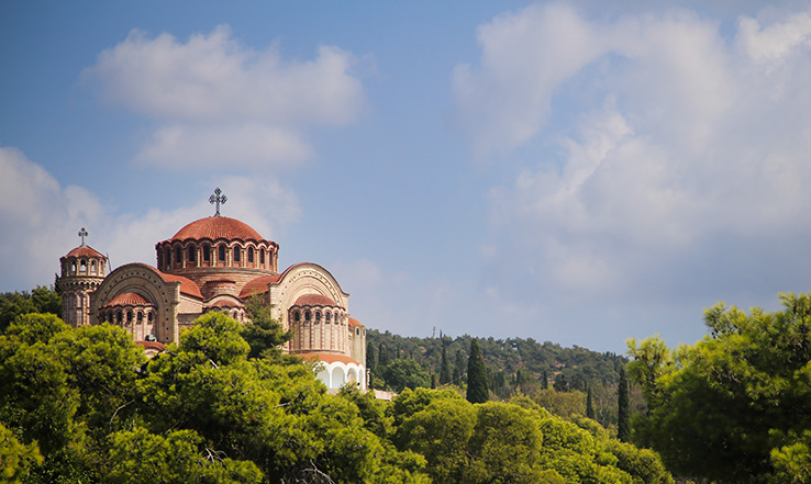 An old building on a hillside filled with trees. 