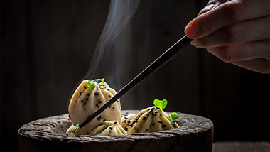 Chopsitck grabbing food out of a bowl. 