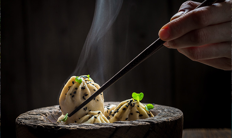 Chopsitck grabbing food out of a bowl. 