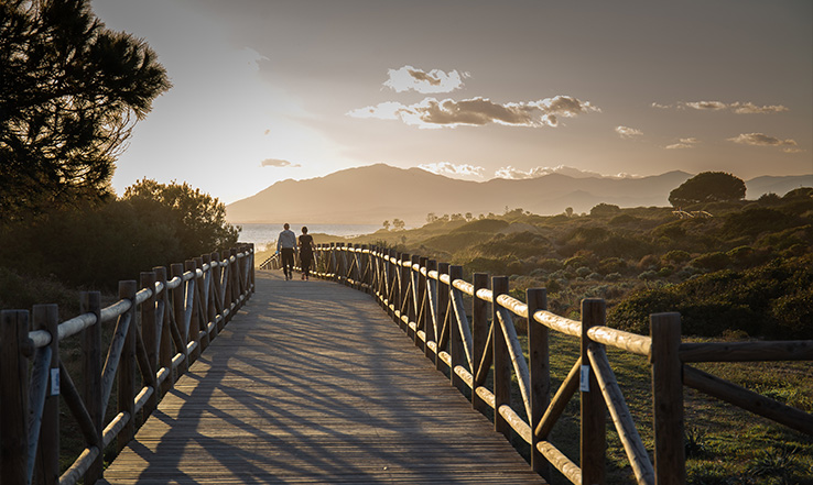 Two people walking on a bridge during a sunrise. 