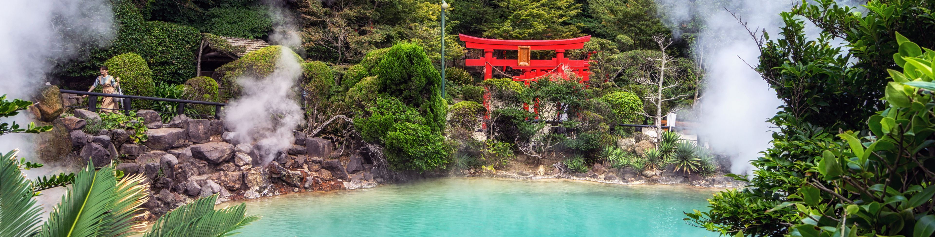 Clear blue water surrounded by steam, trees, and a shrine entrance. 