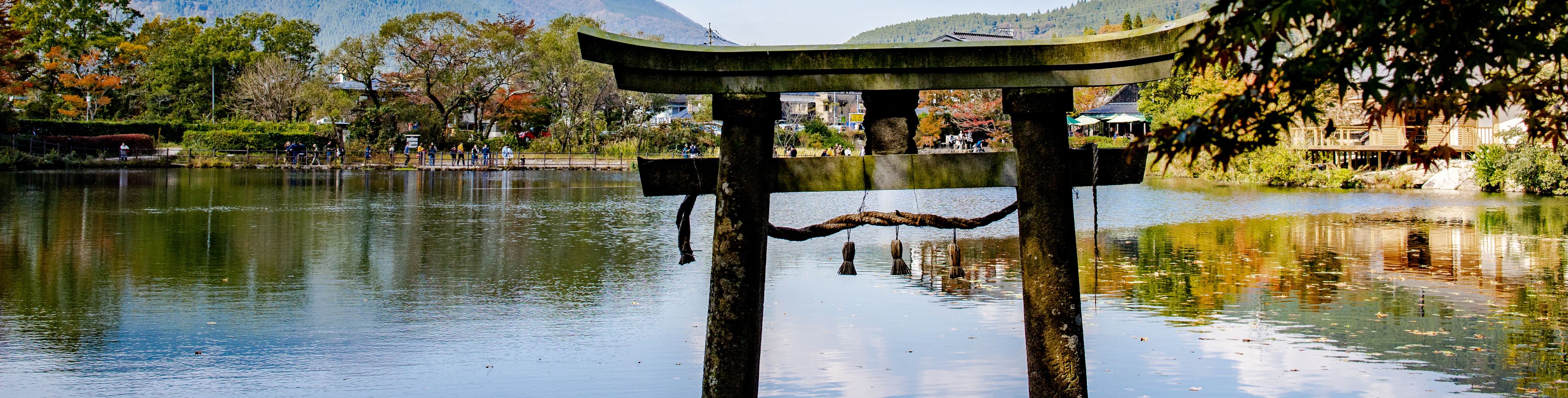 Shrine on the water with village and mountain in the background. 