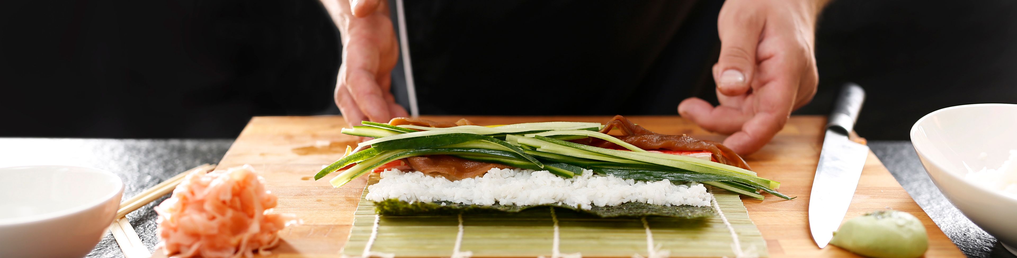 Chef preparing sushi on a cutting board. 