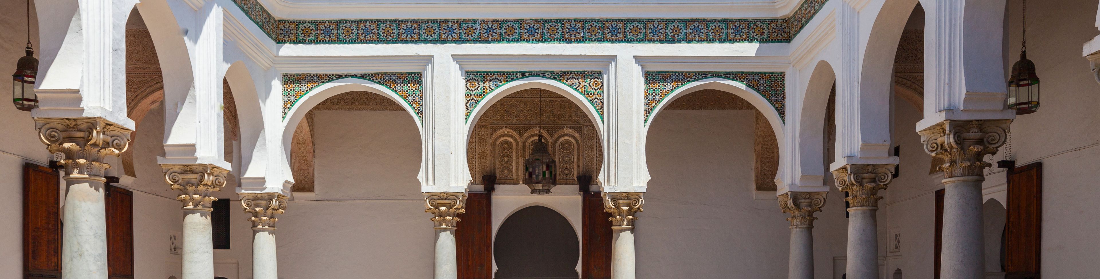 White building with columns and a fountain in the middle of the courtyard. 