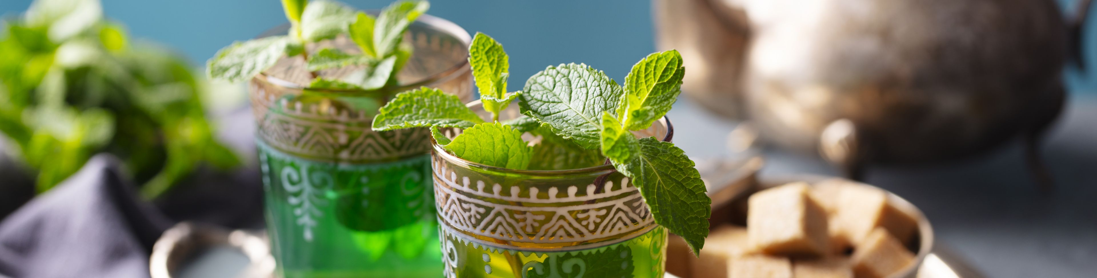 Tea in two small clear cups, with small bread squares in a bowl. 