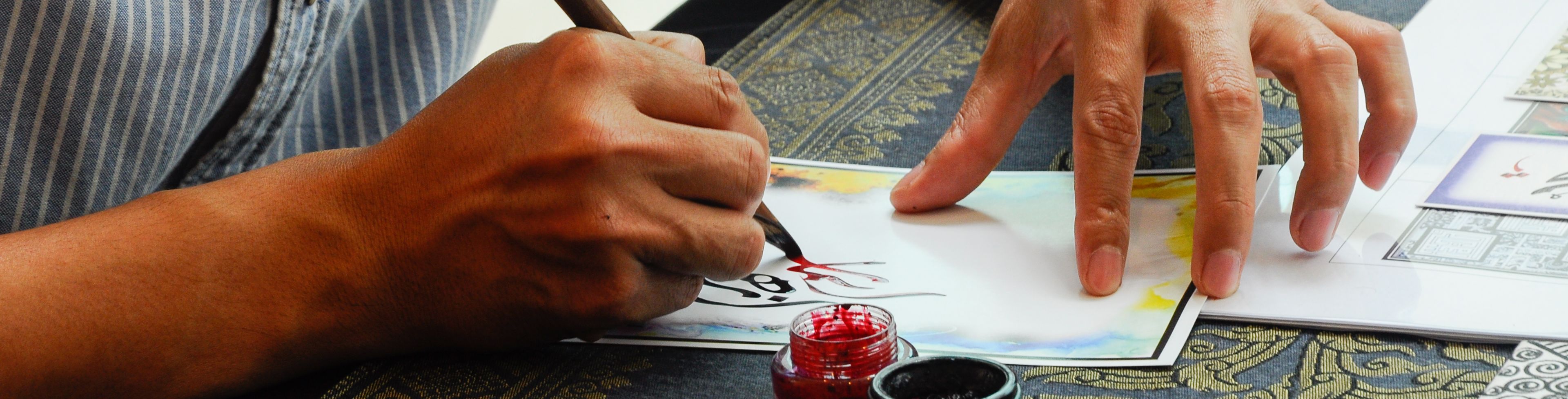 Person using ink to paint on a parchment paper. 