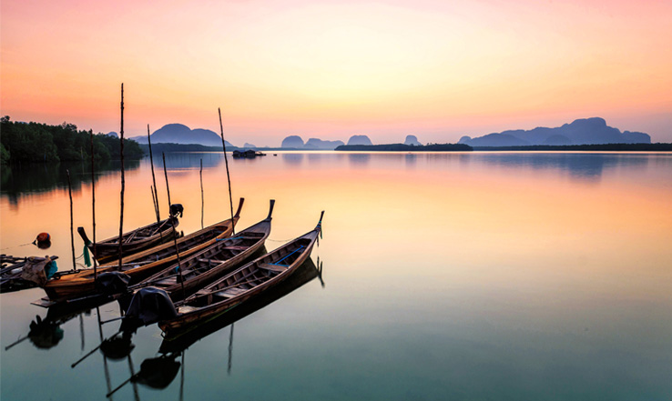 Canoes anchored on the water at sunset. 