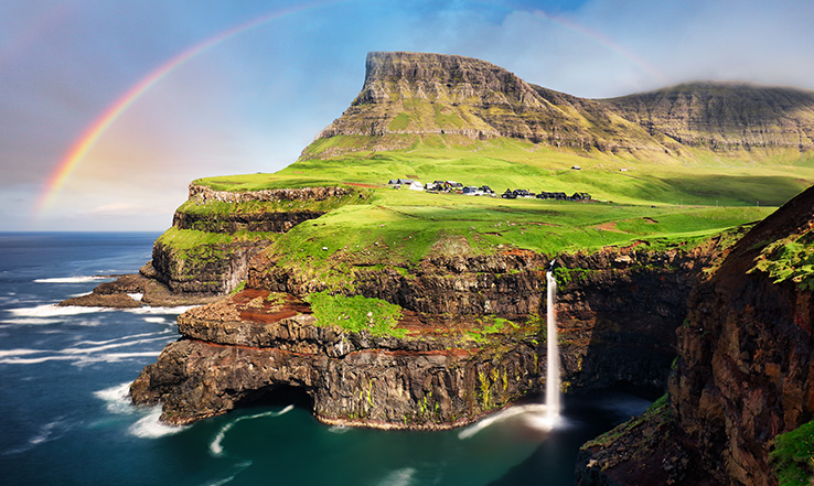 Rainbow in the sky over a land and mountain structure. 