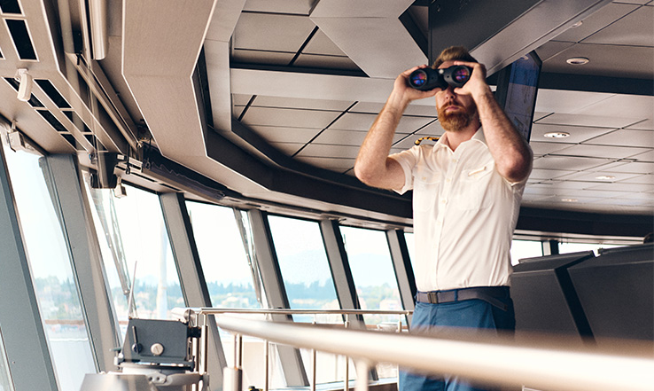 Man using binoculars to look out to sea. 