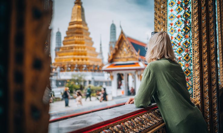 A woman looking out at a view of the Grand Palace in Bangok. 
