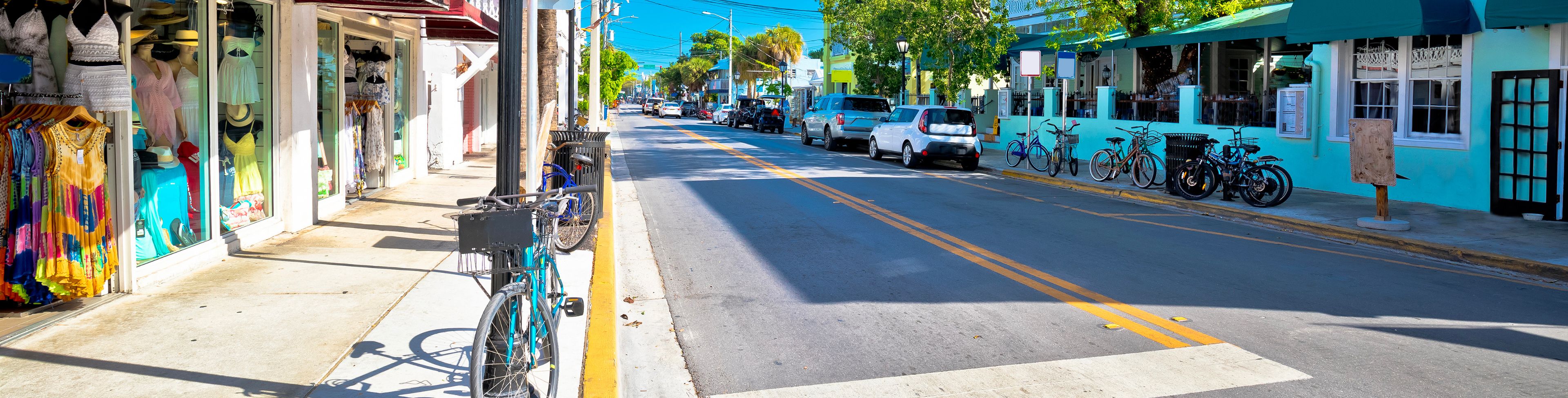 Empty street with bicycles and cars parked in front of buildings. 