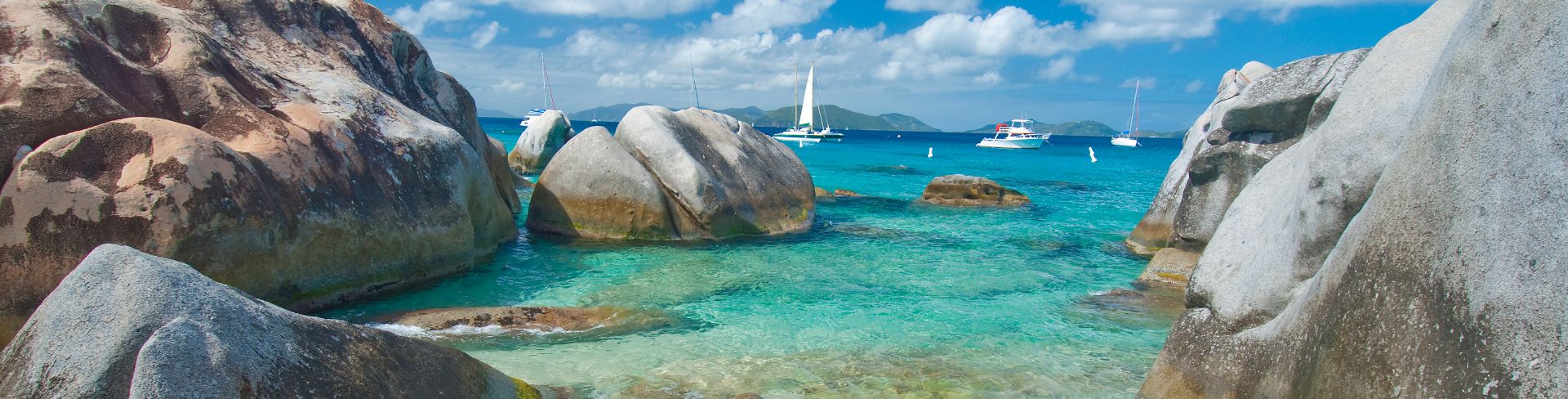 View from shore, large smooth rocks scattered along the shoreline of the ocean. 
