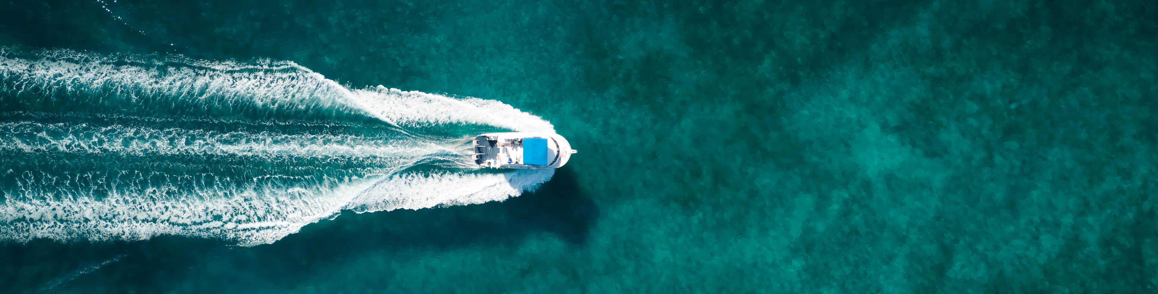 Aerial view of boat driving on top of ocean water. 