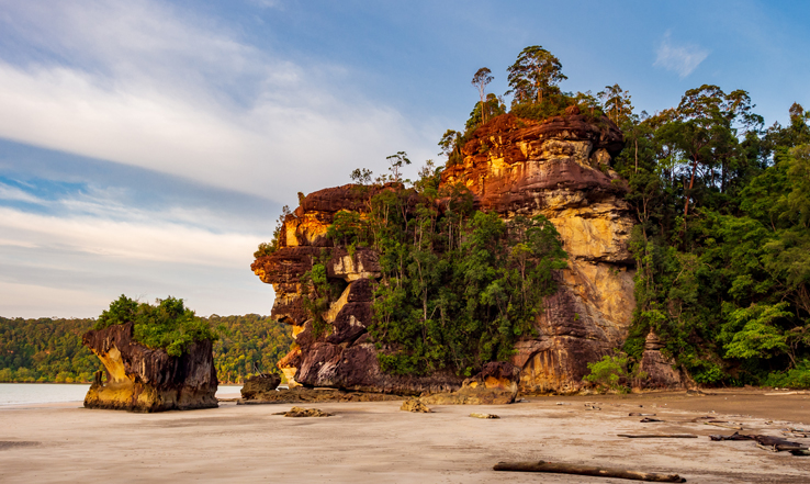 A house on an edge of a cliff, above a beach. 