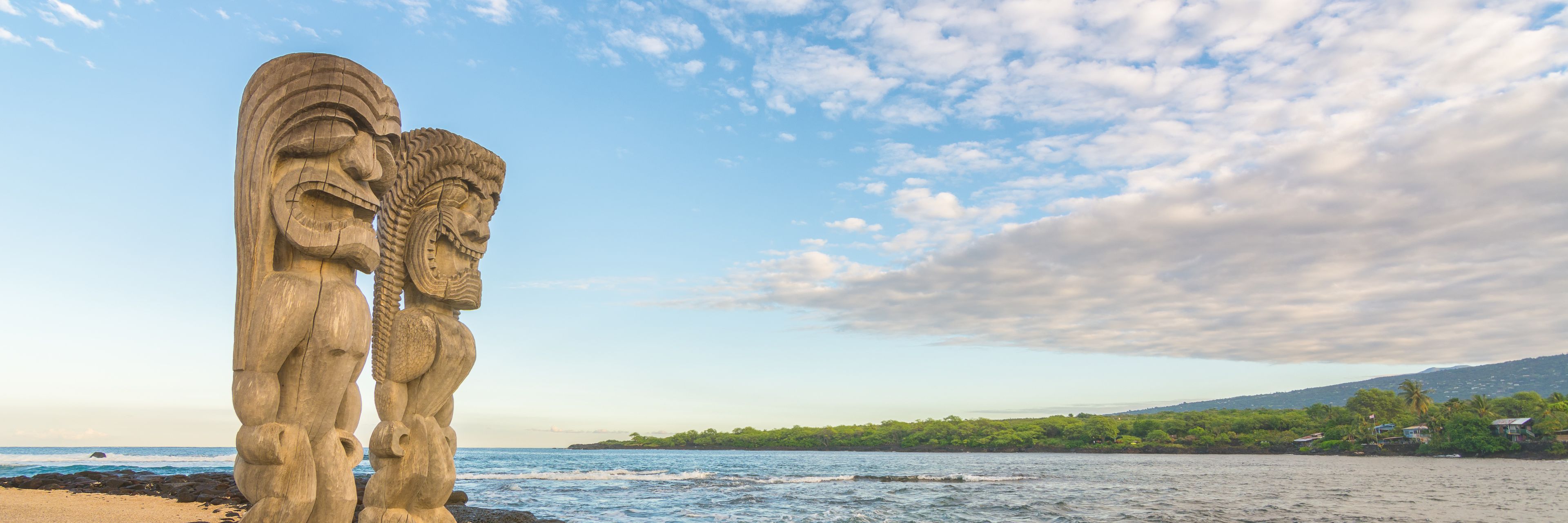 Two statues overlooking the ocean on a rocky shore. 