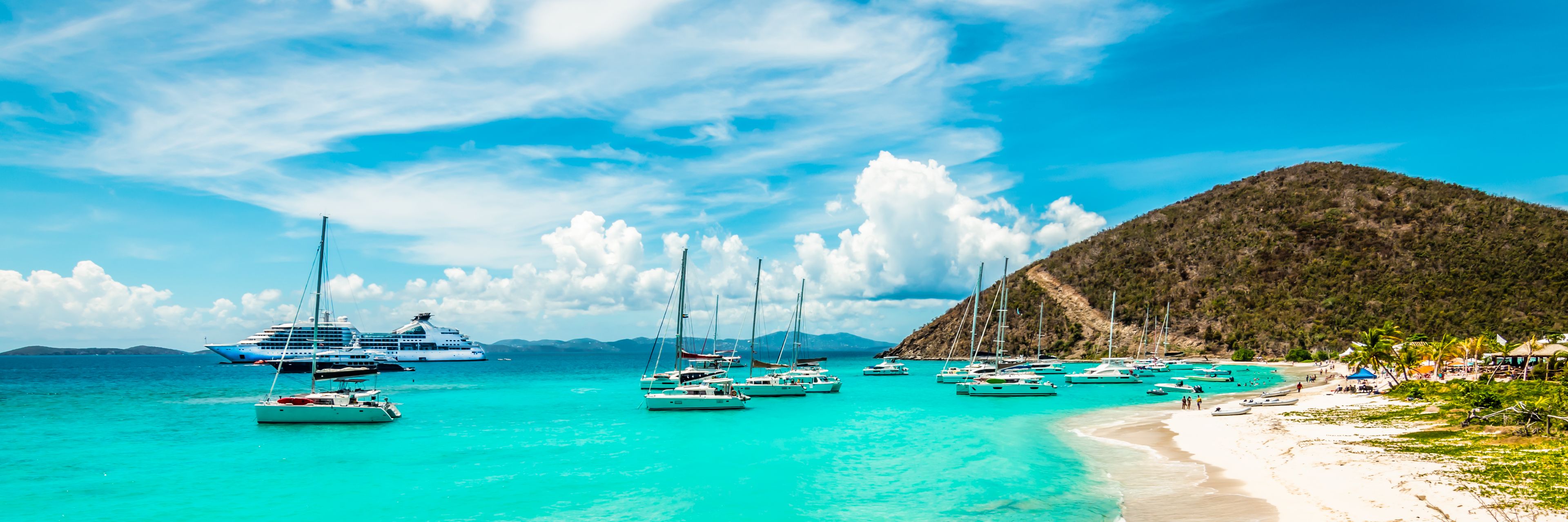 Beach view of sail boats anchored along the shore. 