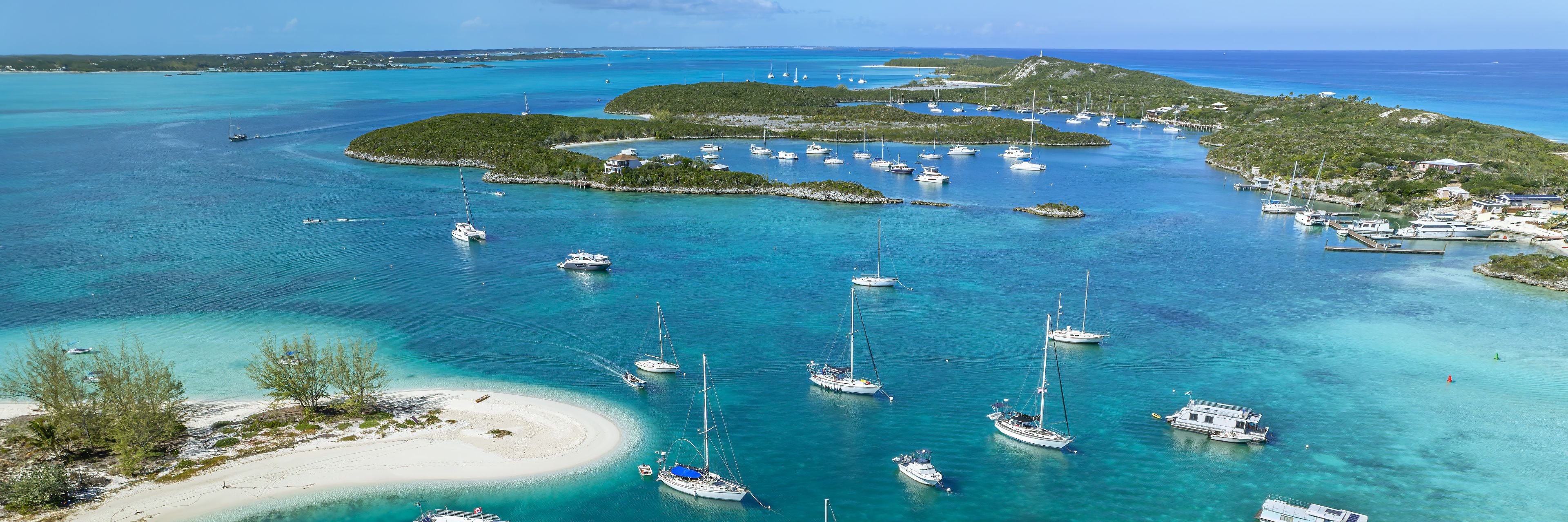 Aerial view of a variety of boats between two island beaches. 