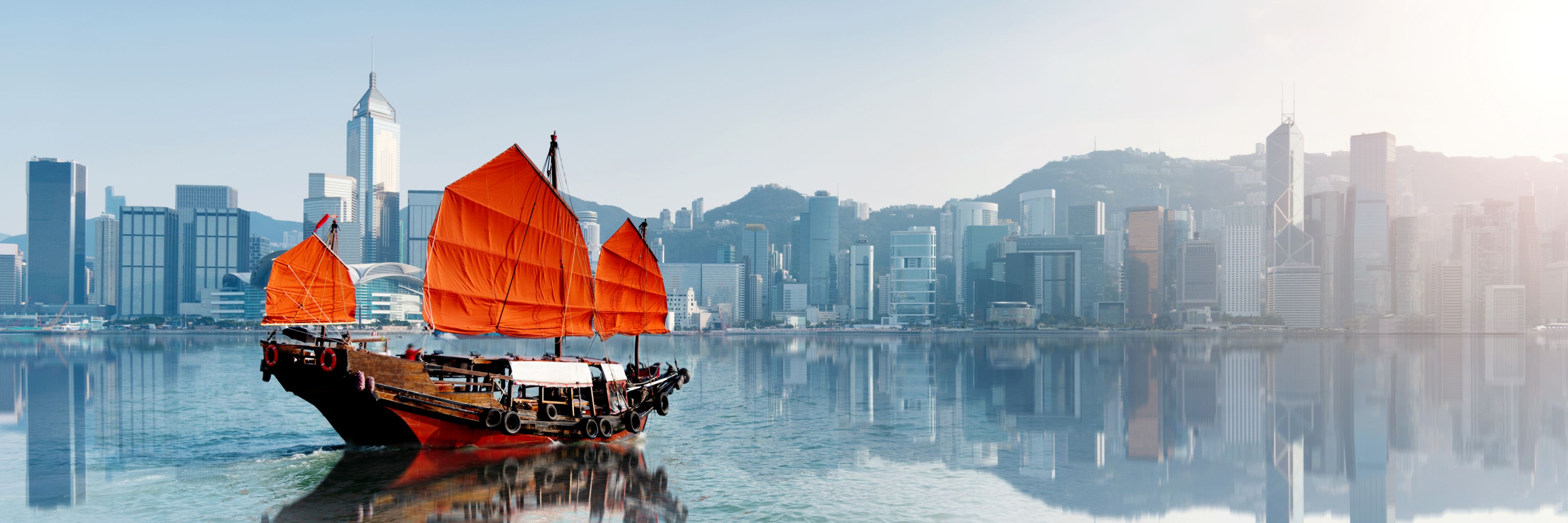 Boat with red sails floating on a body of water in front of Ho Chi Minh City.