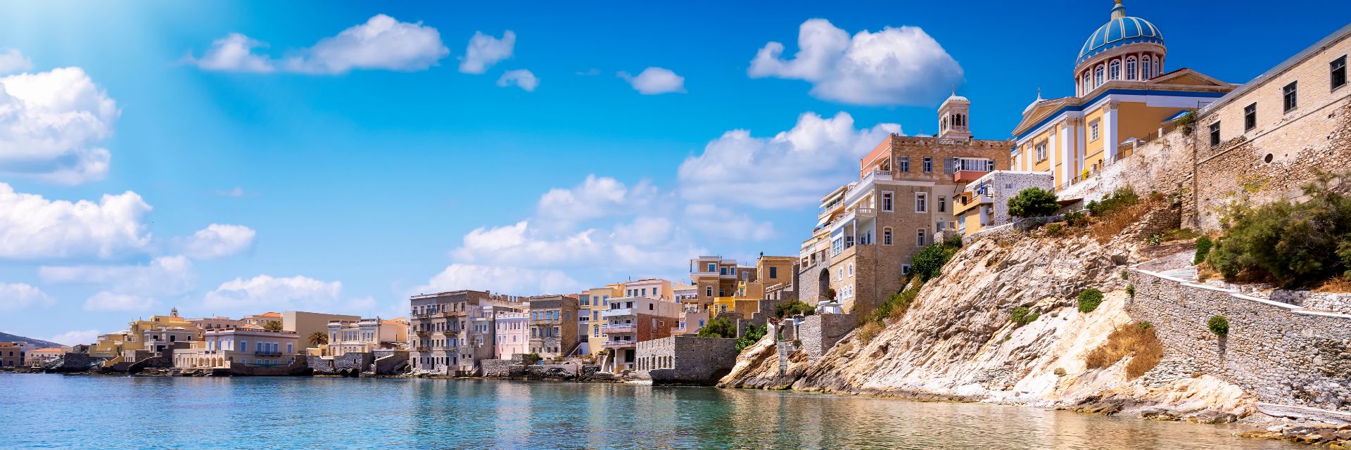 Pastel colored buildings line crystal clear shallow waters.
