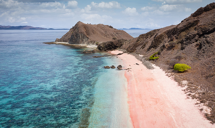 View of a sandy beach and brown hill formation. 
