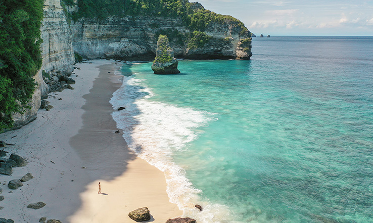 Aerial view of a sandy beach at the bottom of a cliff. 