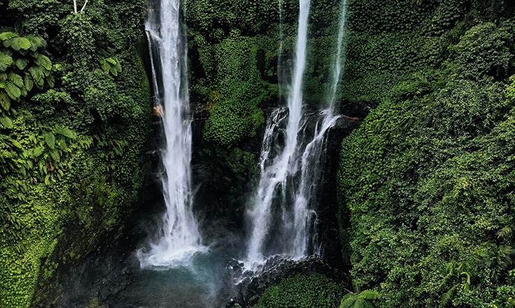 Waterfalls going down a cliff into a body of water. 