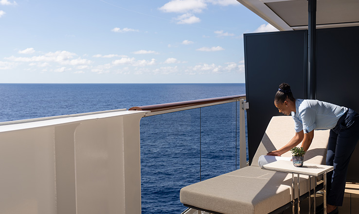 Person setting towel on lounge chair on a deck.