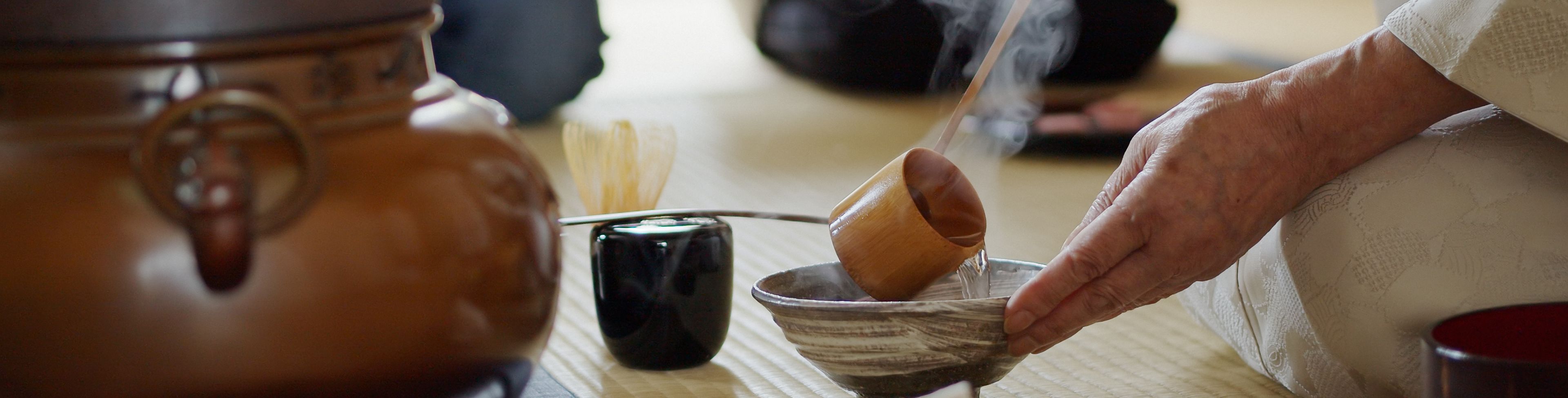 Someone pouring liquid into a small bowl while sitting on the floor.