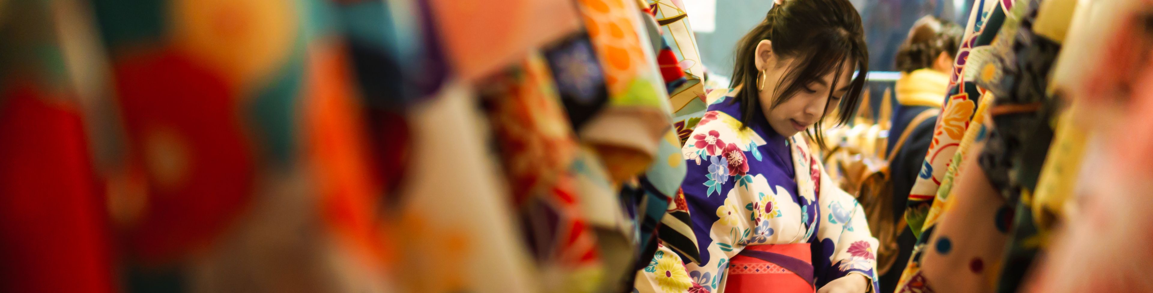 Woman wearing a kimono in a store with other kimono's. 