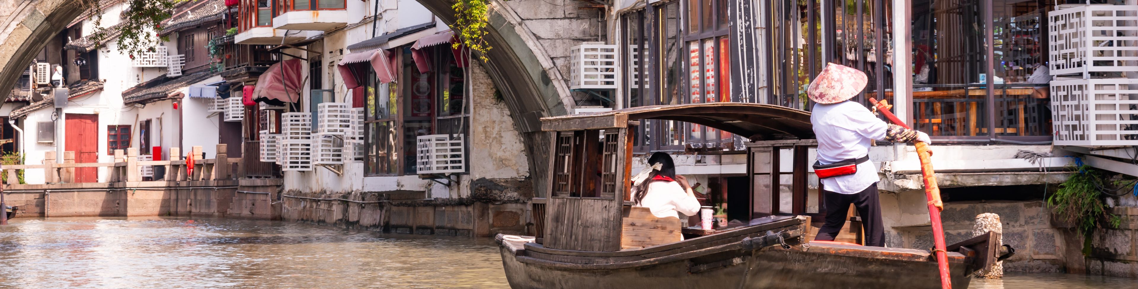 Person guiding a boat through Shanghai waters that run along the city. 