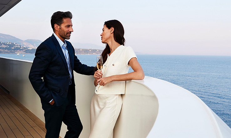 Man and woman looking at each other near railing of the yacht. 