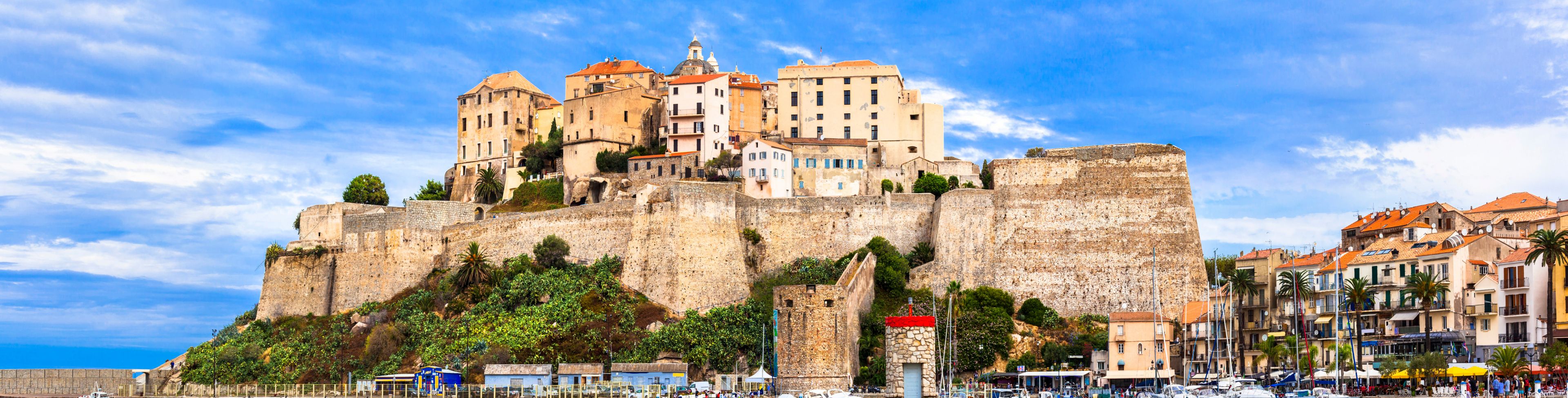Large buildings on the top of a cliffside overlooking the ocean. 