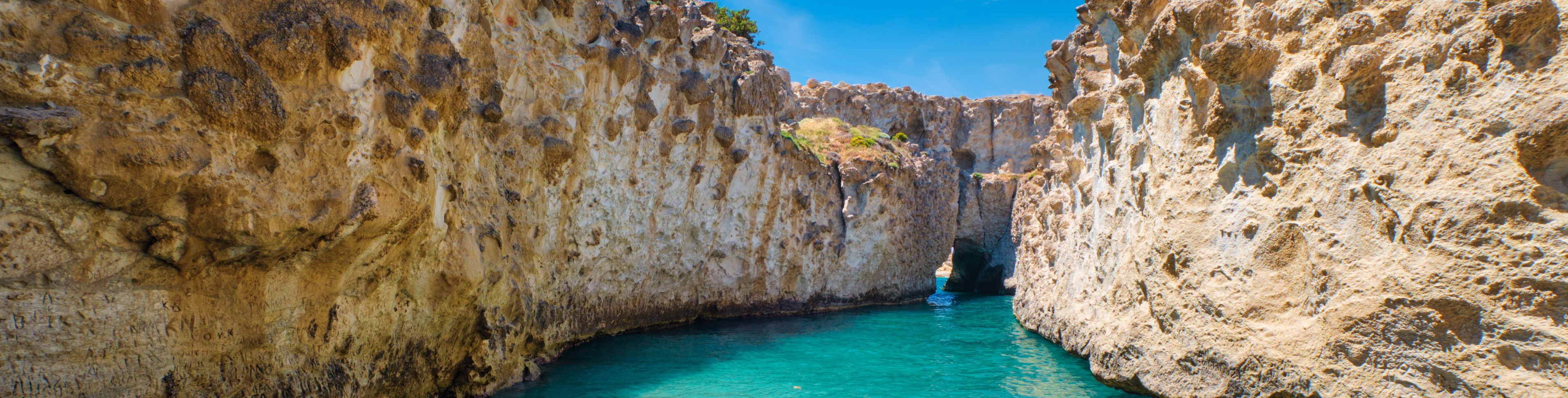 Crystal clear water and beach between two rocky cliffs.