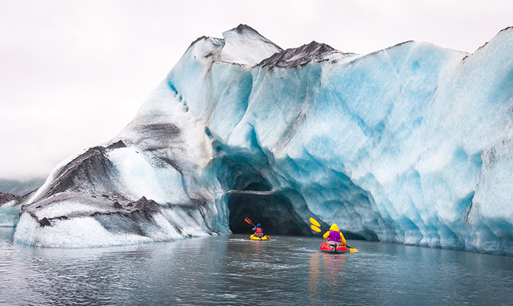 People kayaking througha glacier.
