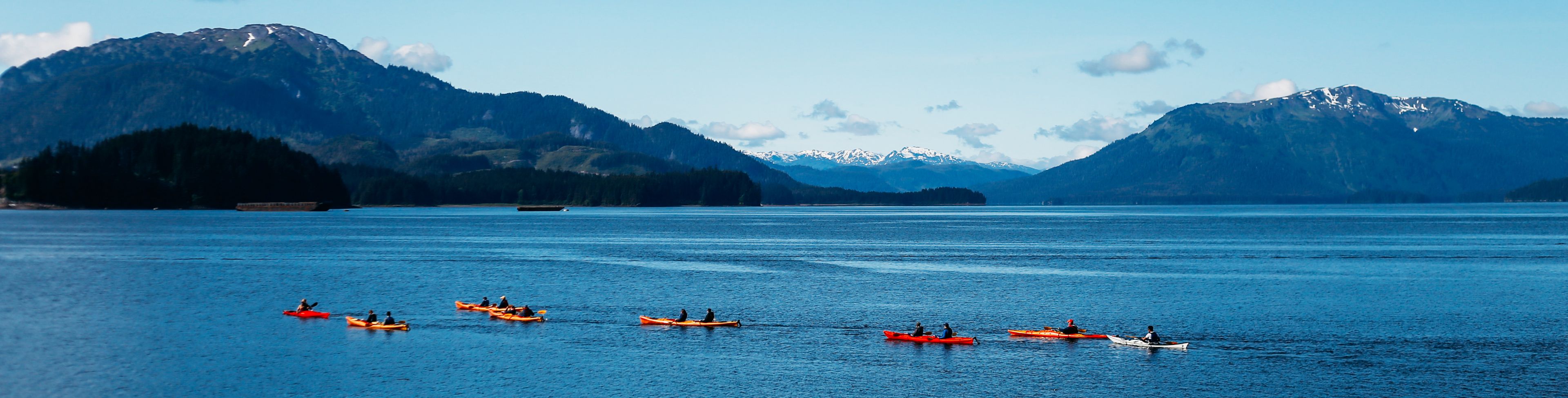 People kayaking on a lake with mountains in the background. 