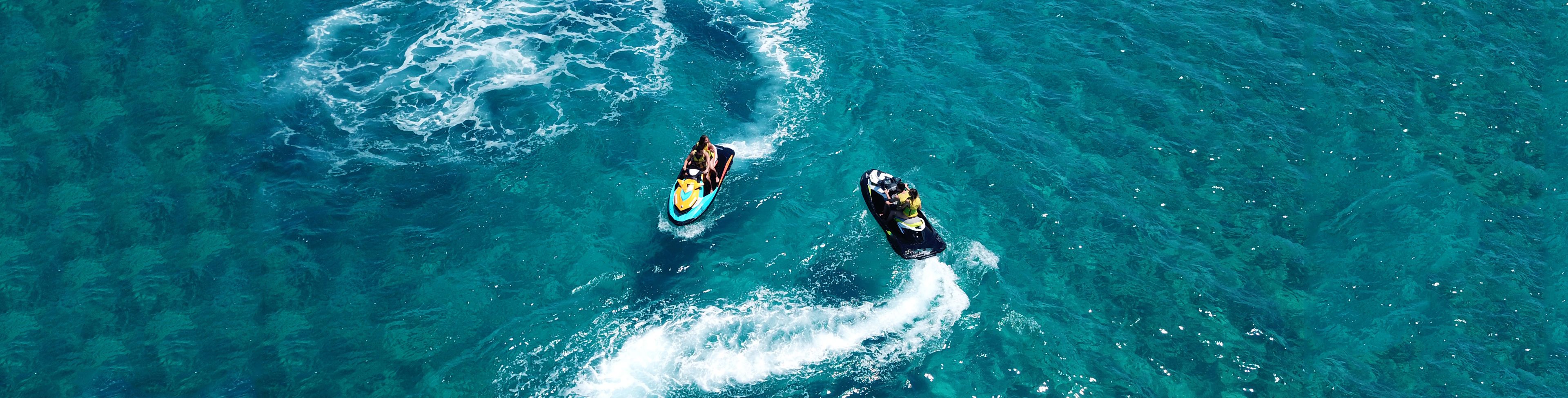 Two jet skis going around each other on the ocean water.