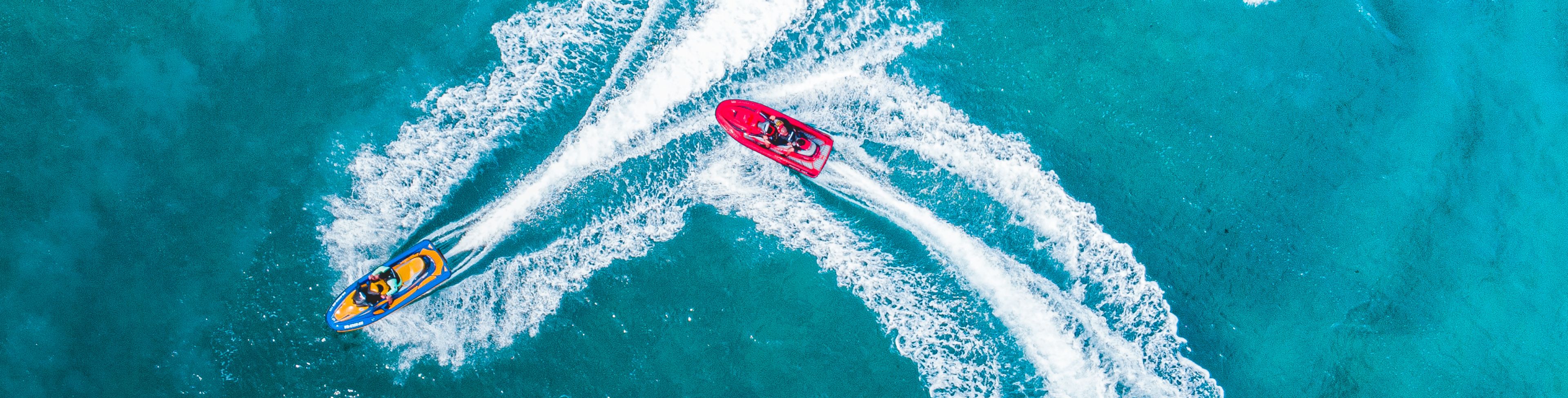 Two people on two jet skis driving on the water around each other. 