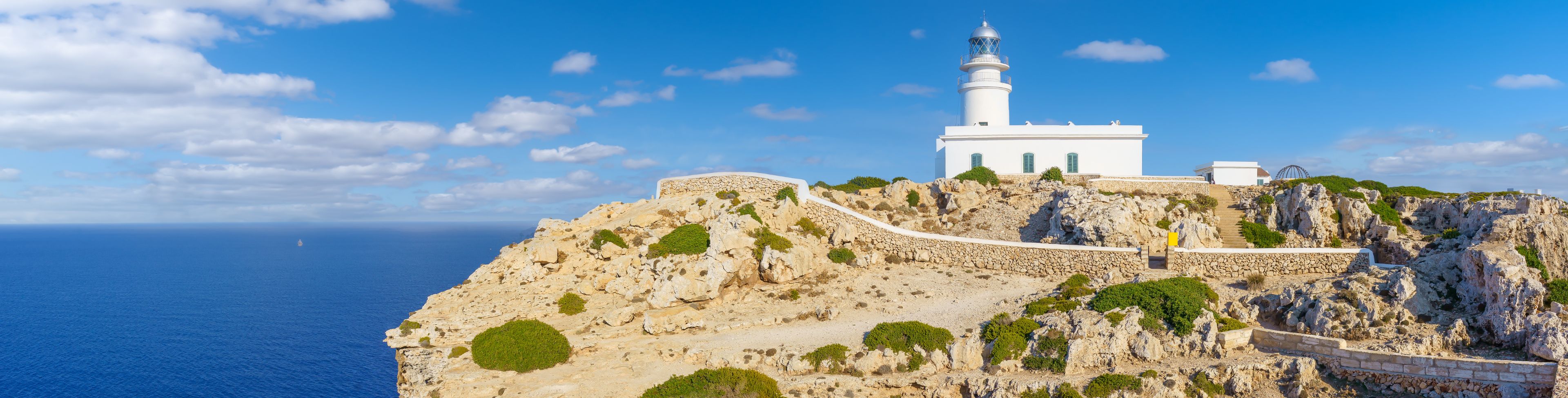 A church sits atop a rocky cliffside overlooking the water.