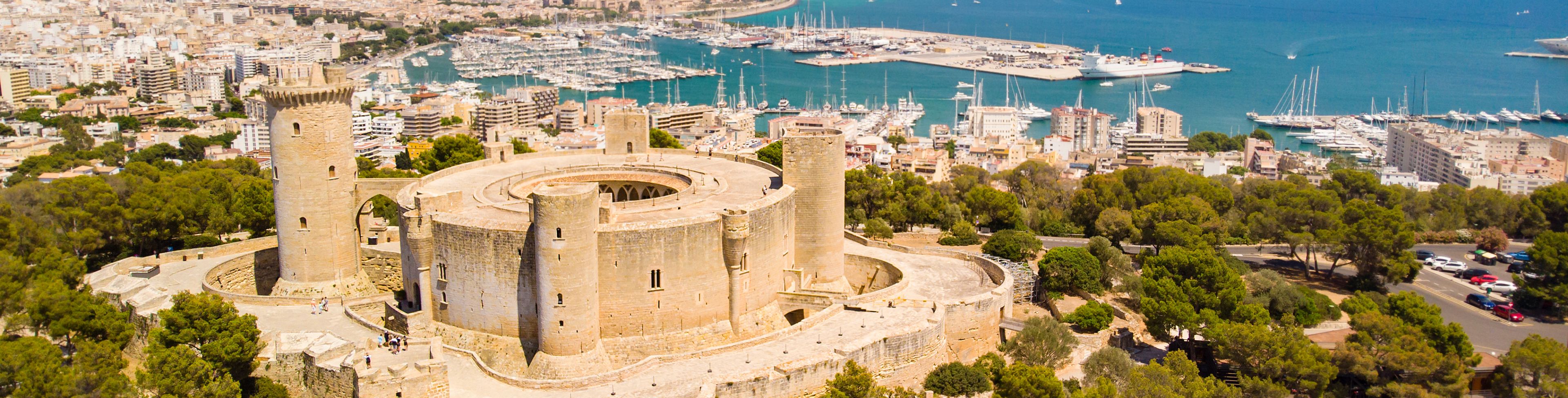 An old building overlooks the city with the coast in the background.