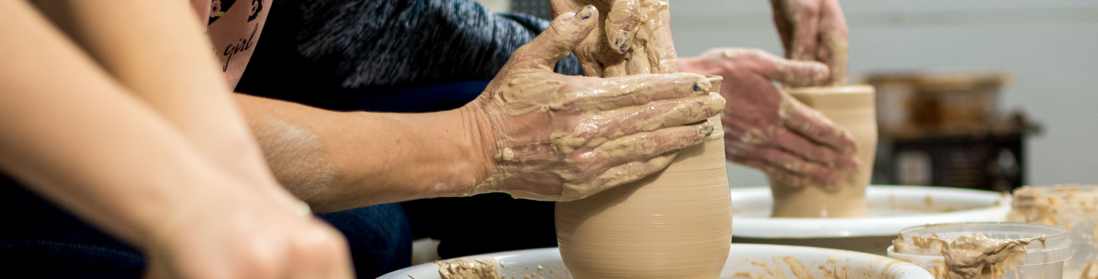 People forming clay on pottery wheels
