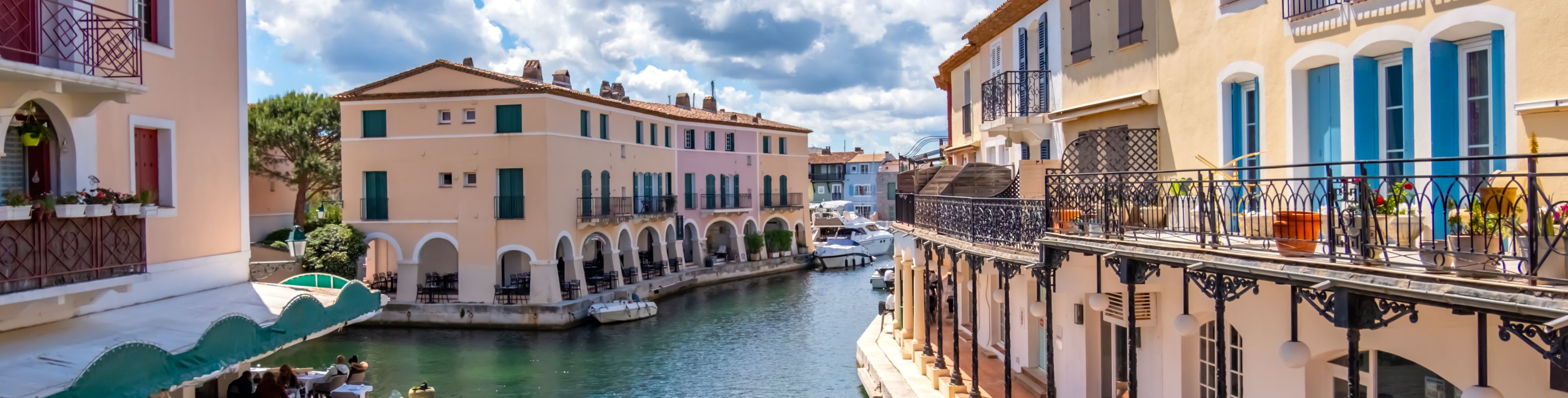 Colorful buildings line a calm canal in St. Tropez, France. 
