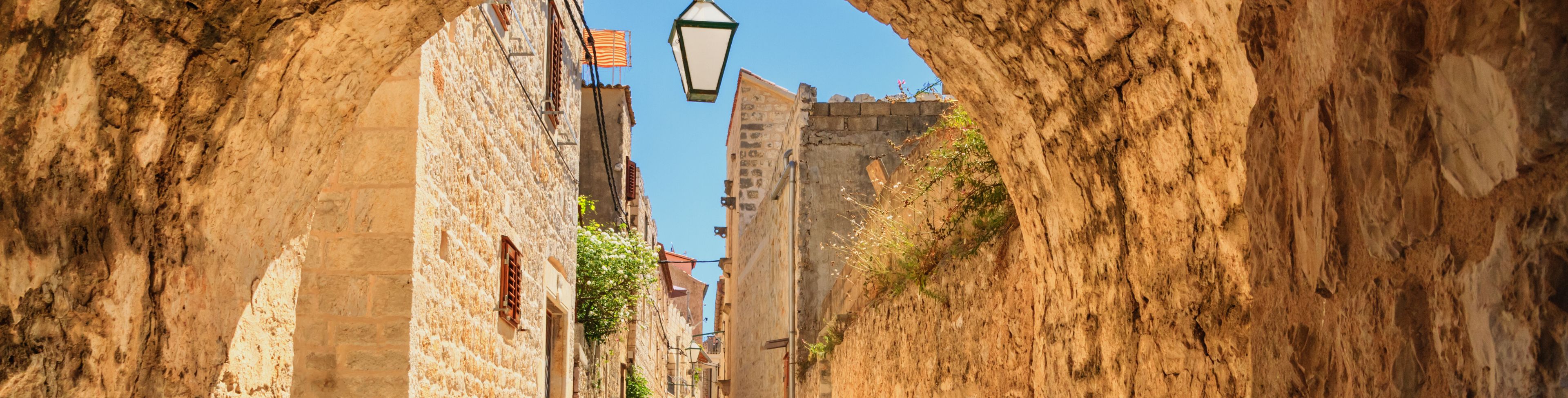 Stone archway with a view of a empty street between stone buildings.